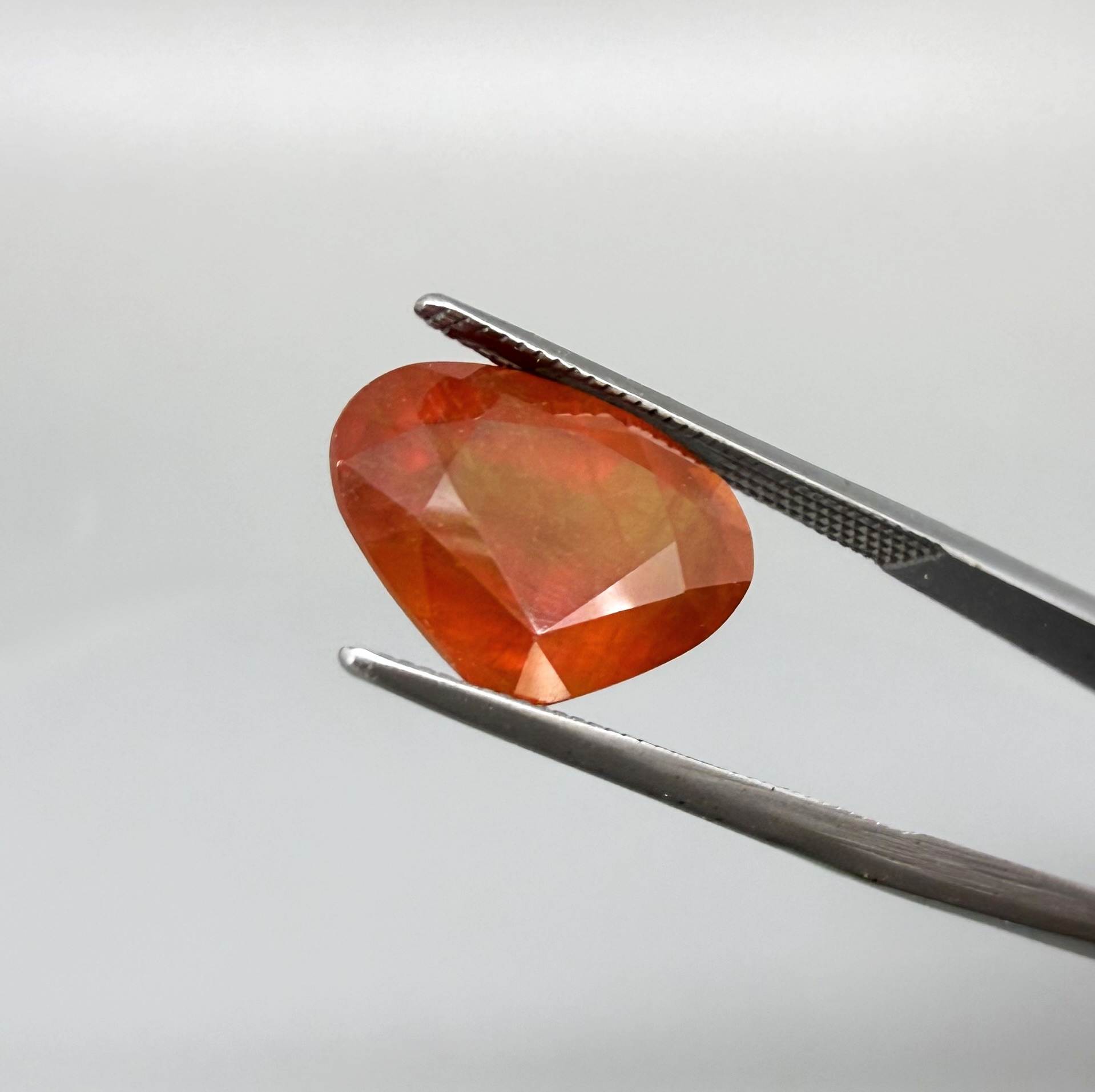 Heart cut orange sapphire from Africa, 6.76ct, with vivid orange to reddish-orange color, visible natural inclusions and a transparent to slightly silky appearance.
