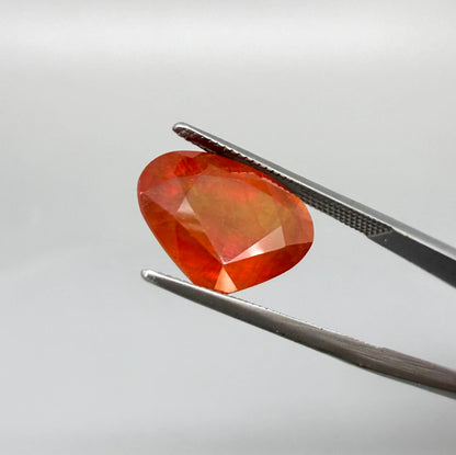 Heart cut orange sapphire from Africa, 6.76ct, with vivid orange to reddish-orange color, visible natural inclusions and a transparent to slightly silky appearance.