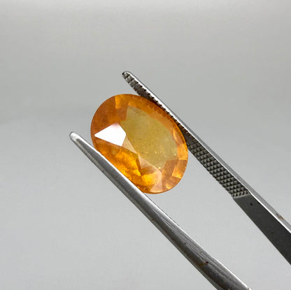 Oval orange sapphire from Africa, 6.04ct, with deep orange to amber color, visible natural inclusions and a transparent to slightly silky appearance.