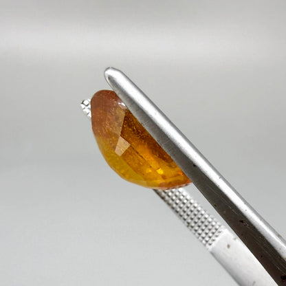 Oval orange sapphire from Africa, 6.04ct, with deep orange to amber color, visible natural inclusions and a transparent to slightly silky appearance.