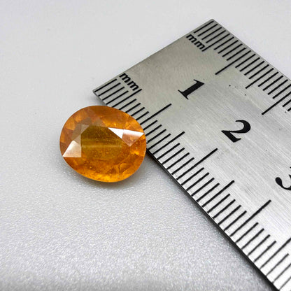 Oval orange sapphire from Africa, 6.04ct, with deep orange to amber color, visible natural inclusions and a transparent to slightly silky appearance.