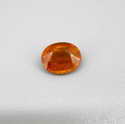 Oval orange sapphire from Africa, 4.43ct, with deep burnt orange color, visible natural inclusions and a transparent to slightly silky appearance.