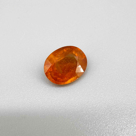 Oval orange sapphire from Africa, 4.43ct, with deep burnt orange color, visible natural inclusions and a transparent to slightly silky appearance.