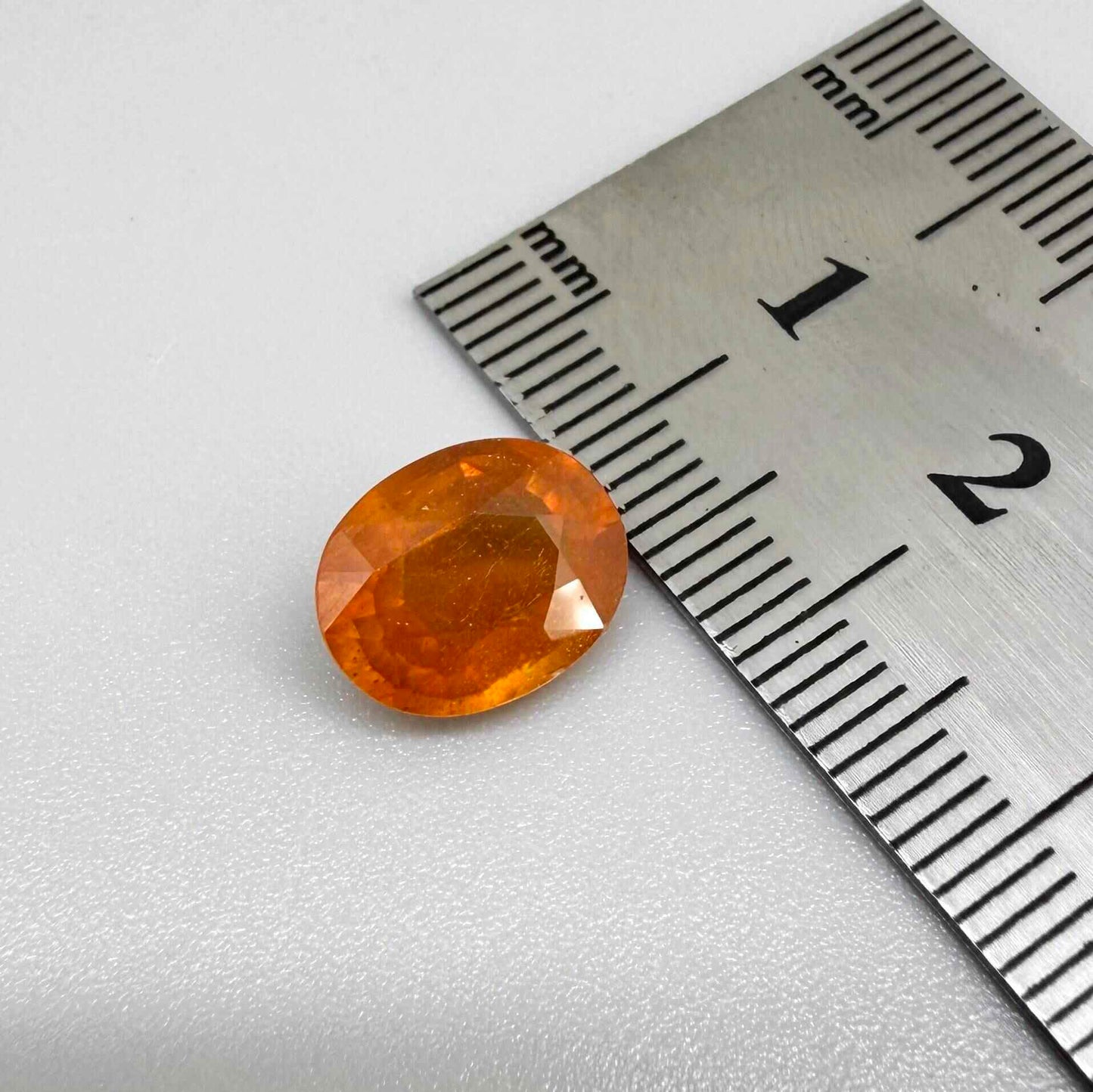 Oval orange sapphire from Africa, 4.43ct, with deep burnt orange color, visible natural inclusions and a transparent to slightly silky appearance.