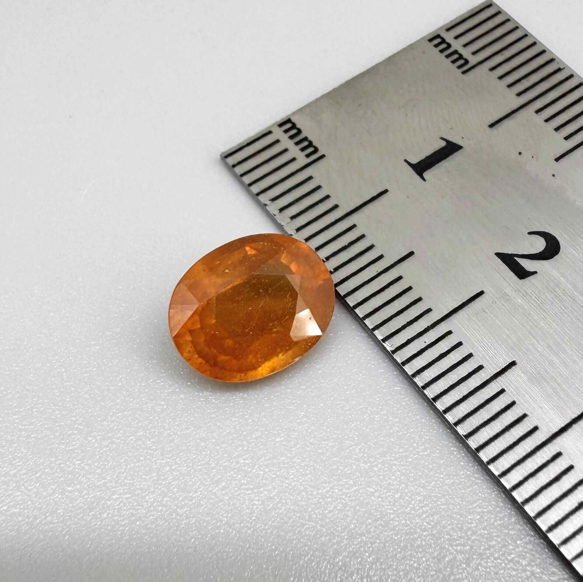 Oval orange sapphire from Africa, 4.43ct, with deep burnt orange color, visible natural inclusions and a transparent to slightly silky appearance.