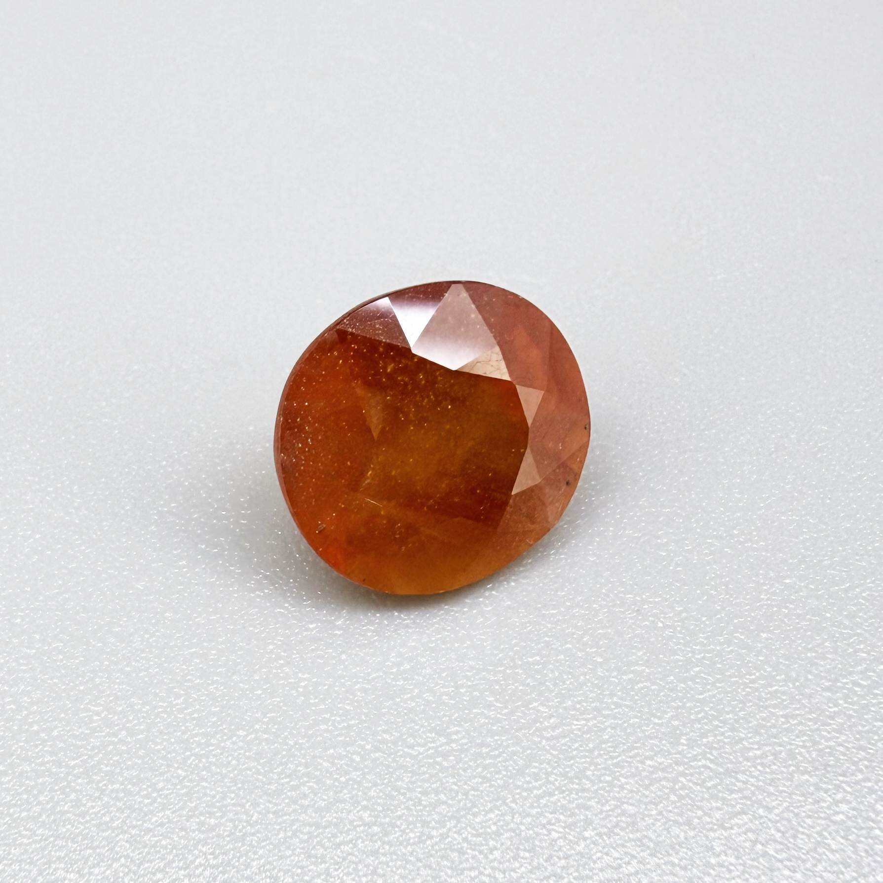 Oval orange sapphire from Africa, 6.2ct, with vivid orange color and a lighter yellowish center, visible natural inclusions and a transparent to slightly silky appearance.