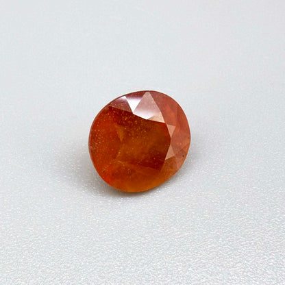 Oval orange sapphire from Africa, 6.2ct, with vivid orange color and a lighter yellowish center, visible natural inclusions and a transparent to slightly silky appearance.