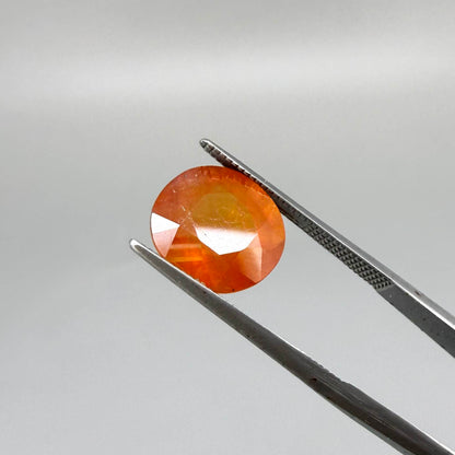 Oval orange sapphire from Africa, 6.2ct, with vivid orange color and a lighter yellowish center, visible natural inclusions and a transparent to slightly silky appearance.