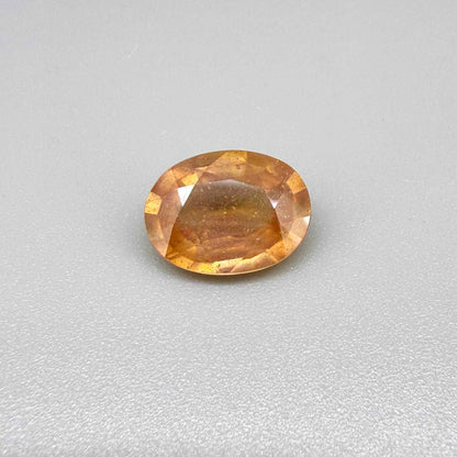 Oval peach to light orange sapphire from Africa, 6.3ct, with soft pastel tones, visible natural inclusions and a transparent to slightly silky appearance.