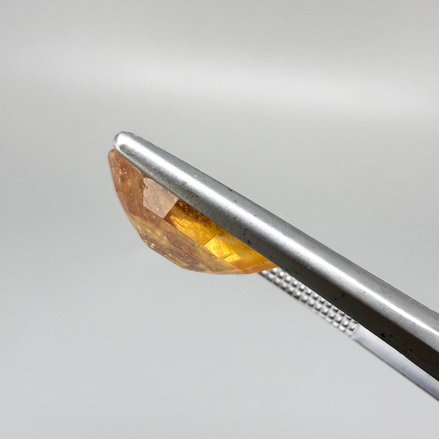 Oval peach to light orange sapphire from Africa, 6.3ct, with soft pastel tones, visible natural inclusions and a transparent to slightly silky appearance.