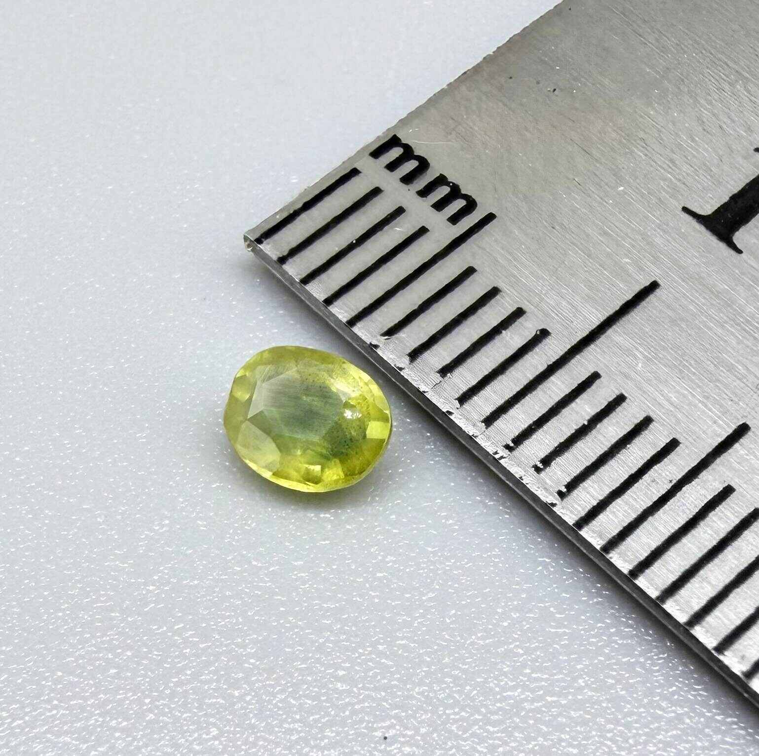 Oval greenish yellow sapphire from Thailand, 0.35ct, unheated, with bright yellow-dominant color and green undertones, visible natural inclusions and a transparent to slightly silky appearance.