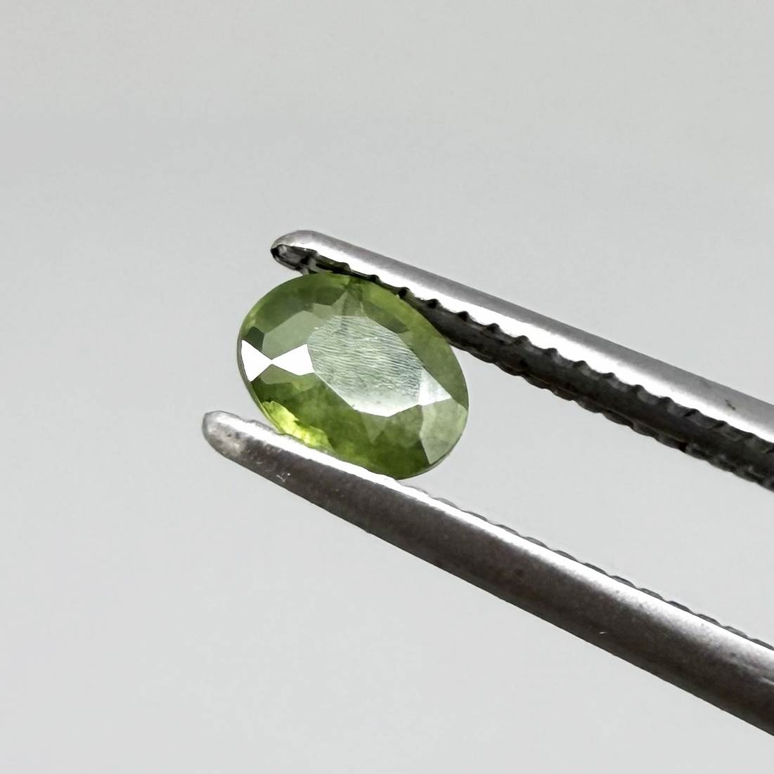 Oval green sapphire from Thailand, 0.35ct, unheated, with rich olive-green color, visible natural inclusions and a transparent to slightly silky appearance.