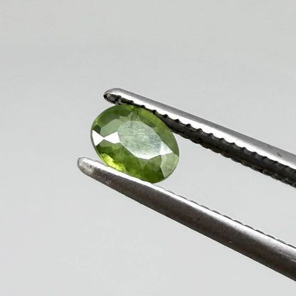Oval green sapphire from Thailand, 0.35ct, unheated, with rich olive-green color, visible natural inclusions and a transparent to slightly silky appearance.