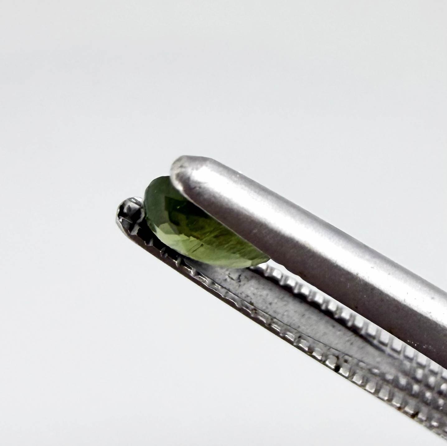Oval green sapphire from Thailand, 0.35ct, unheated, with rich olive-green color, visible natural inclusions and a transparent to slightly silky appearance.