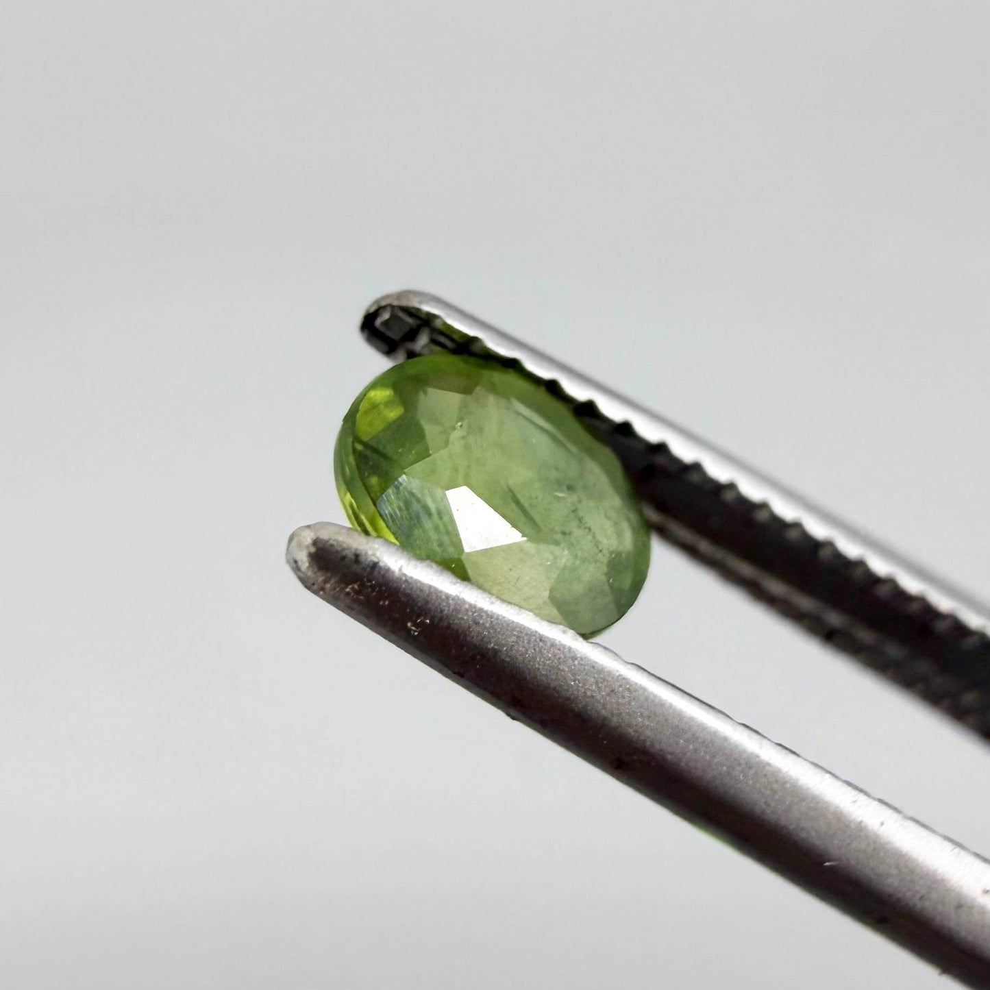 Oval green sapphire from Thailand, 0.35ct, unheated, with rich olive-green color, visible natural inclusions and a transparent to slightly silky appearance.