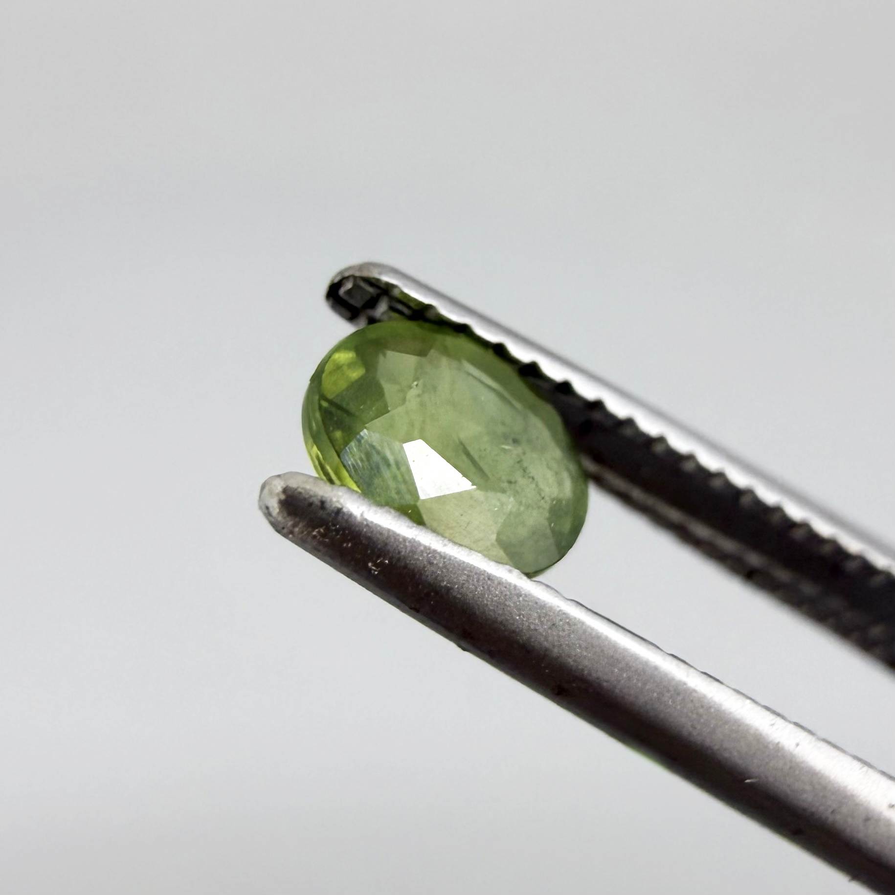 Oval green sapphire from Thailand, 0.35ct, unheated, with rich olive-green color, visible natural inclusions and a transparent to slightly silky appearance.