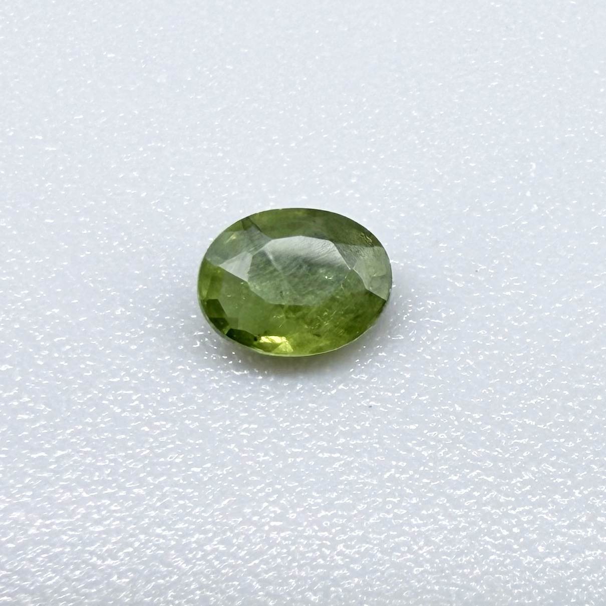 Oval green sapphire from Thailand, 0.35ct, unheated, with rich olive-green color, visible natural inclusions and a transparent to slightly silky appearance.