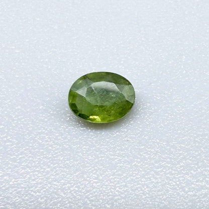 Oval green sapphire from Thailand, 0.35ct, unheated, with rich olive-green color, visible natural inclusions and a transparent to slightly silky appearance.