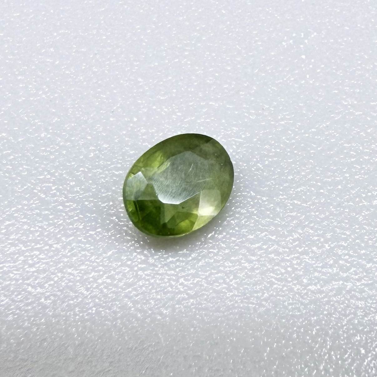 Oval green sapphire from Thailand, 0.35ct, unheated, with rich olive-green color, visible natural inclusions and a transparent to slightly silky appearance.
