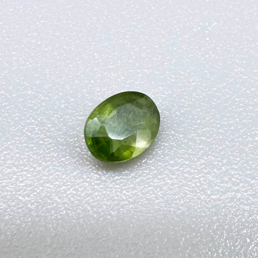 Oval green sapphire from Thailand, 0.35ct, unheated, with rich olive-green color, visible natural inclusions and a transparent to slightly silky appearance.