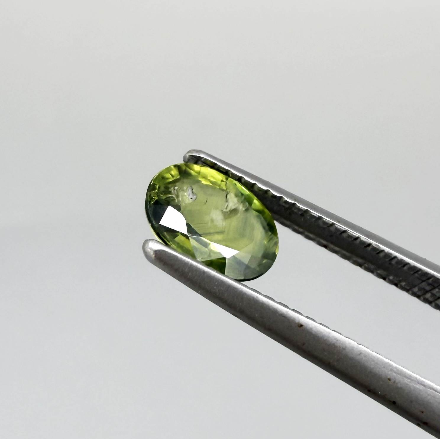 Oval green sapphire from Thailand, 0.5ct, unheated, with deep olive to forest green color, visible natural inclusions and a transparent to slightly silky appearance.