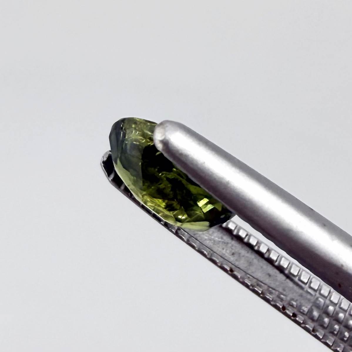 Oval green sapphire from Thailand, 0.5ct, unheated, with deep olive to forest green color, visible natural inclusions and a transparent to slightly silky appearance.