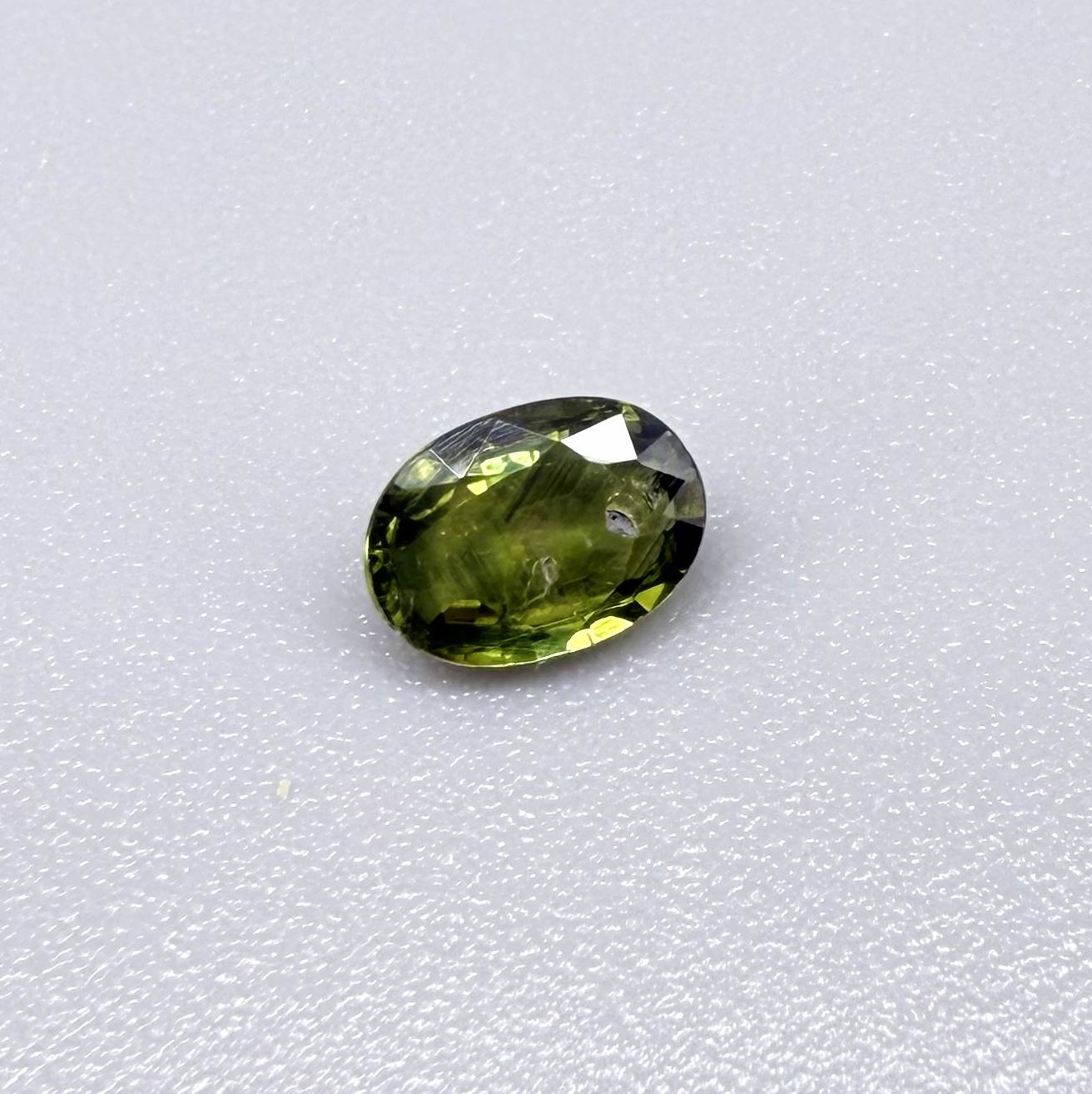 Oval green sapphire from Thailand, 0.5ct, unheated, with deep olive to forest green color, visible natural inclusions and a transparent to slightly silky appearance.
