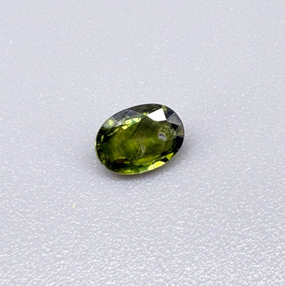 Oval green sapphire from Thailand, 0.5ct, unheated, with deep olive to forest green color, visible natural inclusions and a transparent to slightly silky appearance.