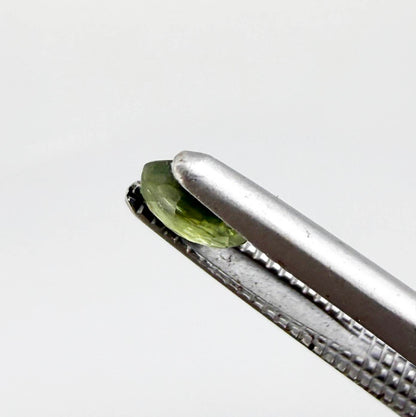 Oval green sapphire from Thailand, 0.37ct, unheated, with olive to deep green color zoning, visible natural inclusions and a transparent to slightly silky appearance.