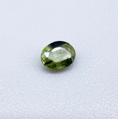 Oval green sapphire from Thailand, 0.37ct, unheated, with olive to deep green color zoning, visible natural inclusions and a transparent to slightly silky appearance.