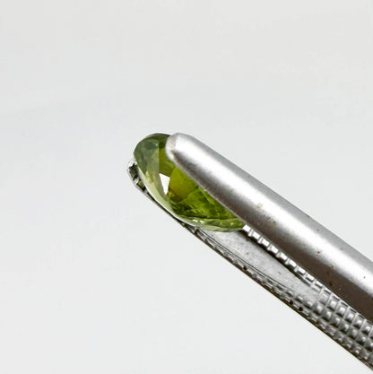 Oval green sapphire from Thailand, 0.54ct, unheated, with olive-green color, visible natural inclusions and a transparent to slightly silky appearance.