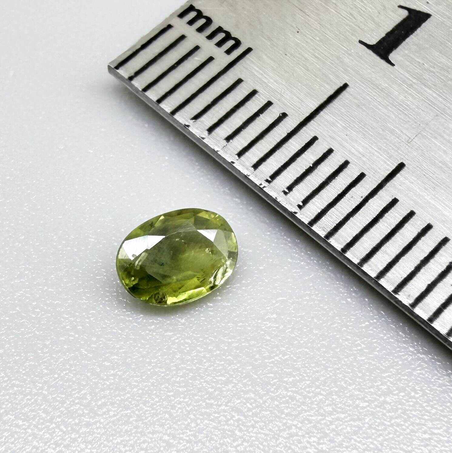 Oval green sapphire from Thailand, 0.54ct, unheated, with olive-green color, visible natural inclusions and a transparent to slightly silky appearance.