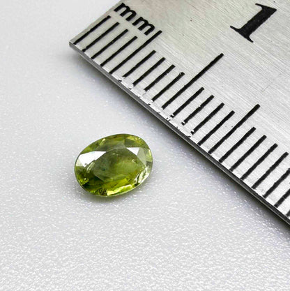 Oval green sapphire from Thailand, 0.54ct, unheated, with olive-green color, visible natural inclusions and a transparent to slightly silky appearance.