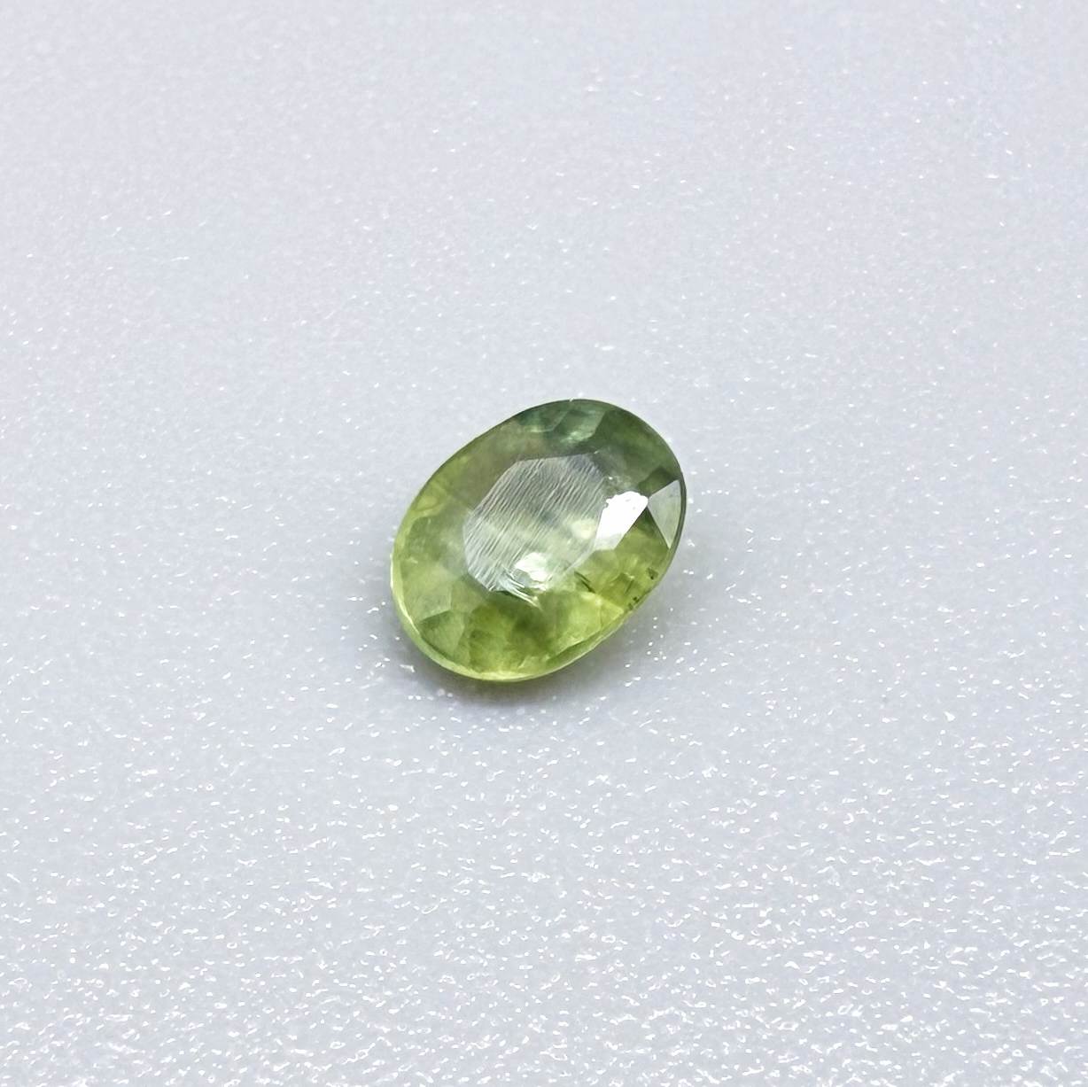 Oval light green sapphire from Thailand, 0.33ct, unheated, with soft green color, visible banding and natural inclusions and a transparent to slightly silky appearance.