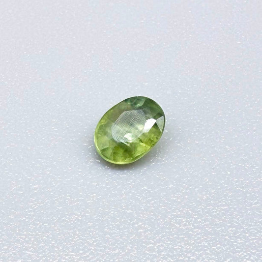 Oval light green sapphire from Thailand, 0.33ct, unheated, with soft green color, visible banding and natural inclusions and a transparent to slightly silky appearance.