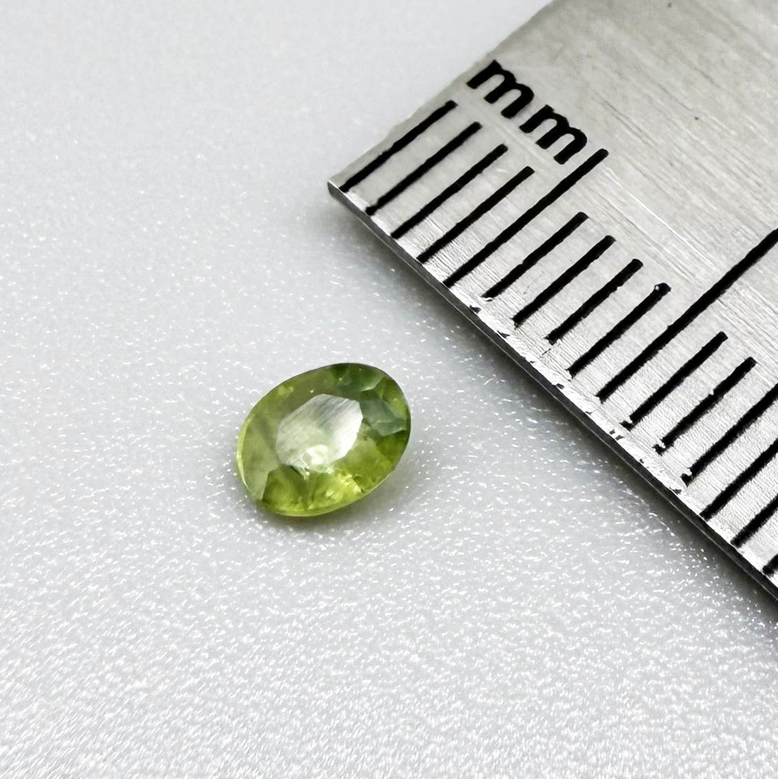 Oval light green sapphire from Thailand, 0.33ct, unheated, with soft green color, visible banding and natural inclusions and a transparent to slightly silky appearance.