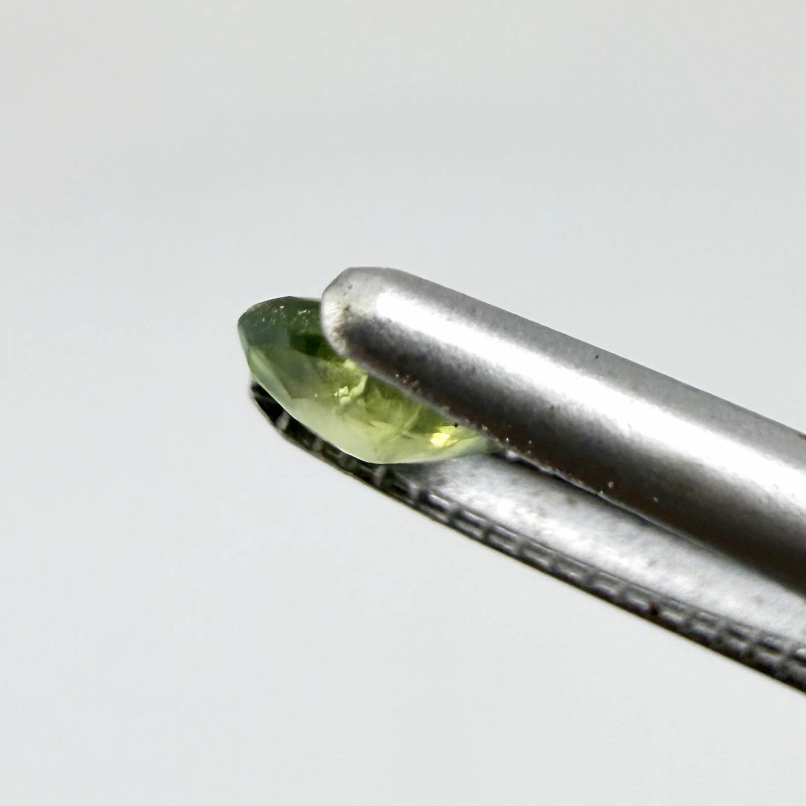 Oval light green sapphire from Thailand, 0.33ct, unheated, with soft green color, visible banding and natural inclusions and a transparent to slightly silky appearance.