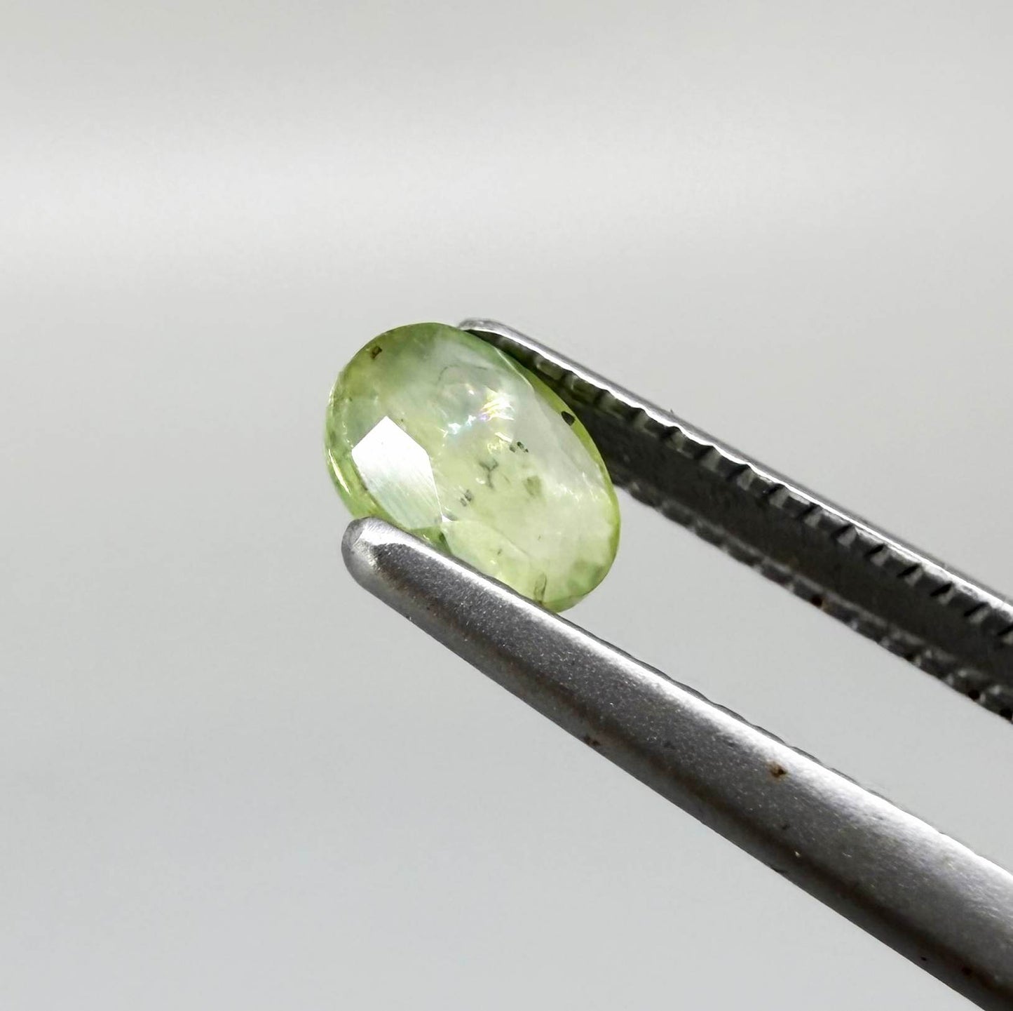 Oval light green sapphire from Thailand, 0.42ct, unheated, with soft pistachio-green color, visible natural inclusions and a transparent to slightly silky appearance.