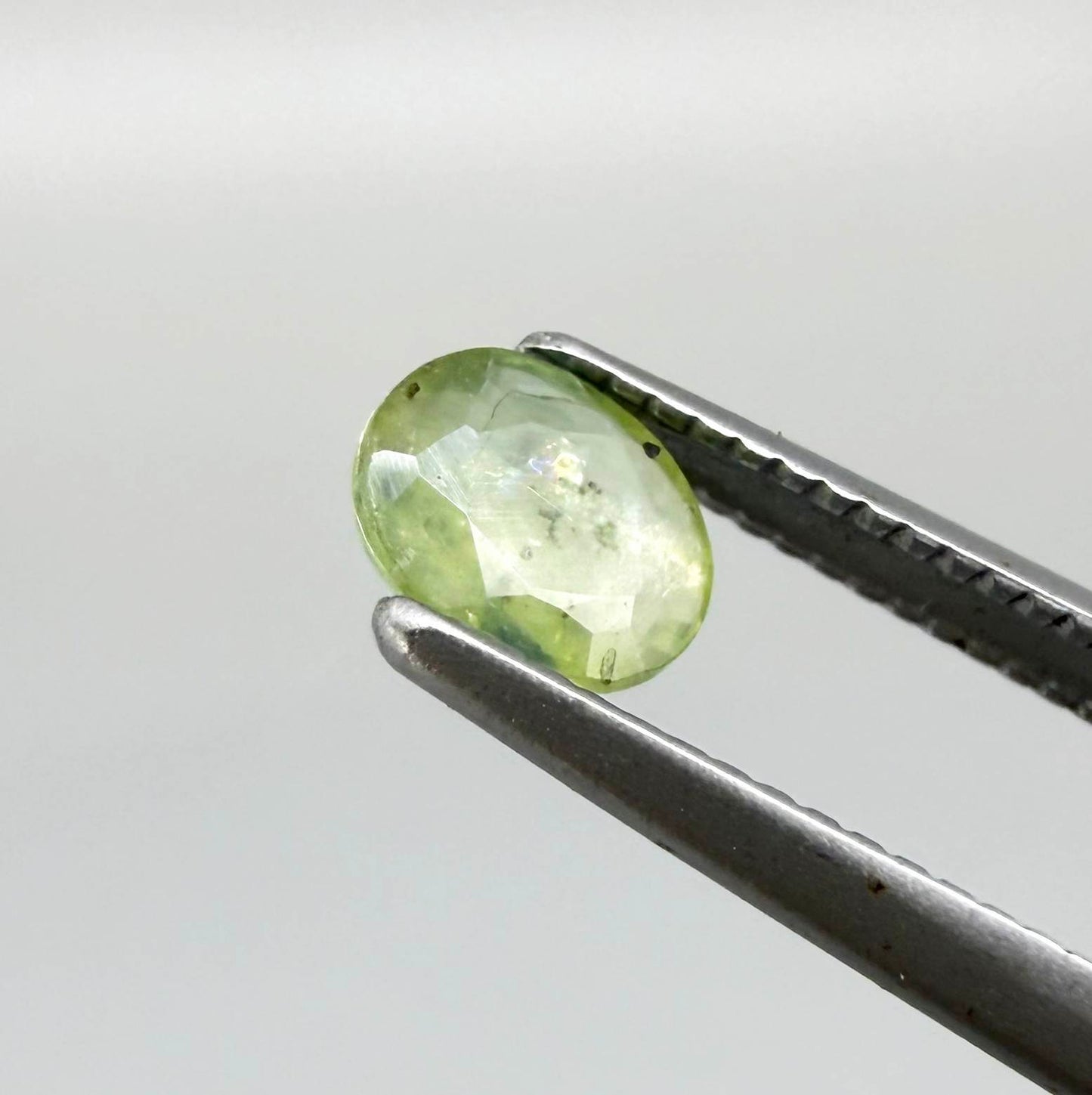 Oval light green sapphire from Thailand, 0.42ct, unheated, with soft pistachio-green color, visible natural inclusions and a transparent to slightly silky appearance.
