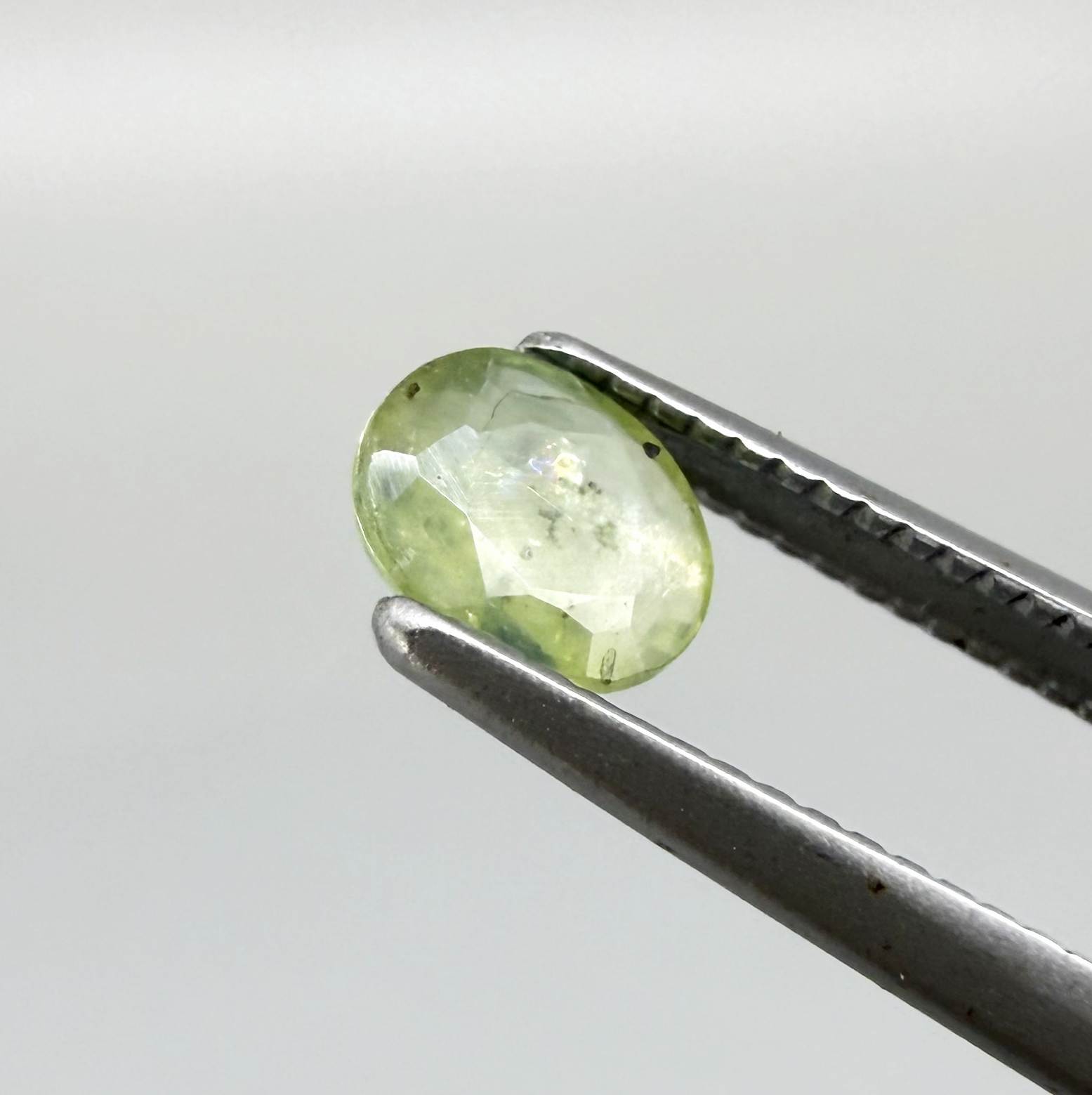 Oval light green sapphire from Thailand, 0.42ct, unheated, with soft pistachio-green color, visible natural inclusions and a transparent to slightly silky appearance.