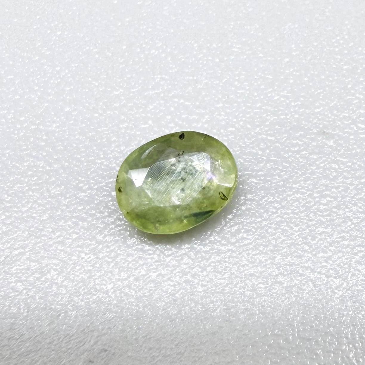 Oval light green sapphire from Thailand, 0.42ct, unheated, with soft pistachio-green color, visible natural inclusions and a transparent to slightly silky appearance.