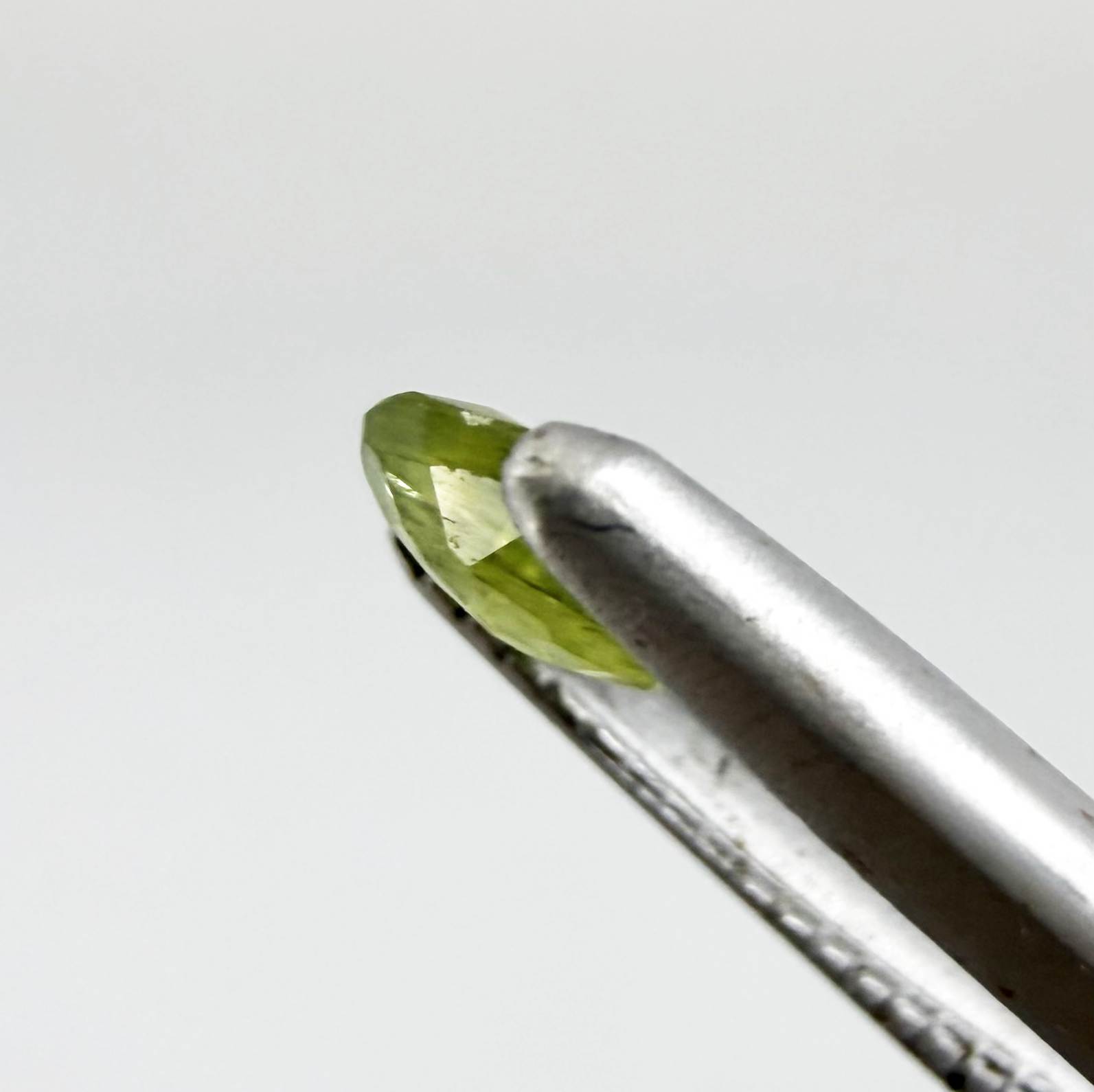 Oval light green sapphire from Thailand, 0.31ct, unheated, with fresh yellow-green color, visible natural inclusions and a transparent to slightly silky appearance.