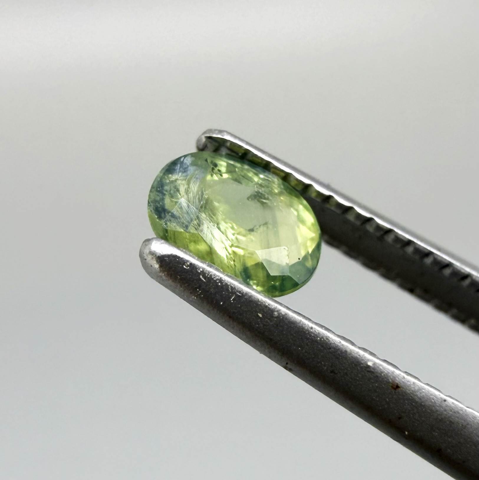Oval green sapphire from Thailand, 0.35ct, unheated, with fresh green hues, visible natural inclusions and a transparent to slightly silky appearance.
