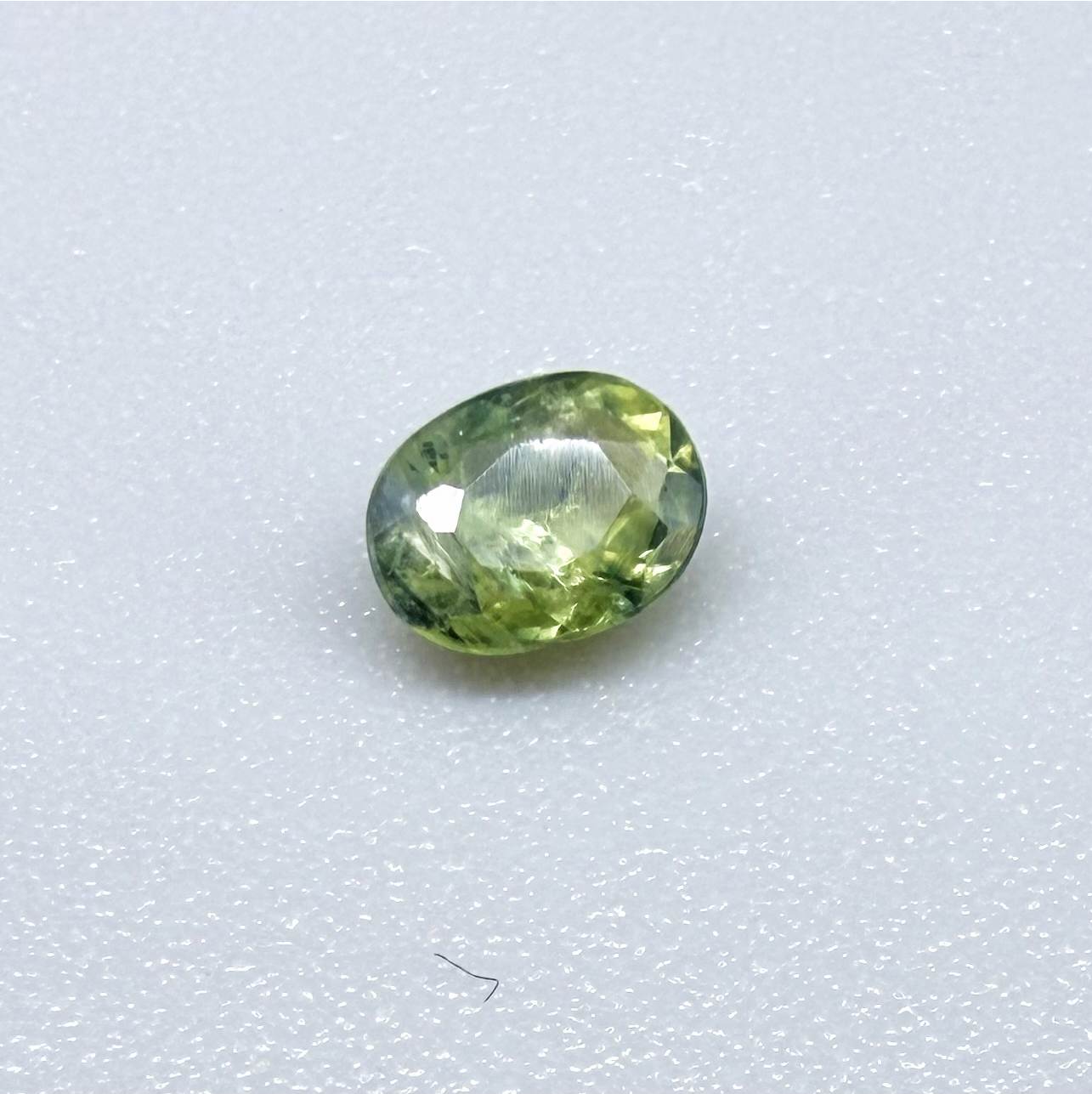 Oval green sapphire from Thailand, 0.35ct, unheated, with fresh green hues, visible natural inclusions and a transparent to slightly silky appearance.