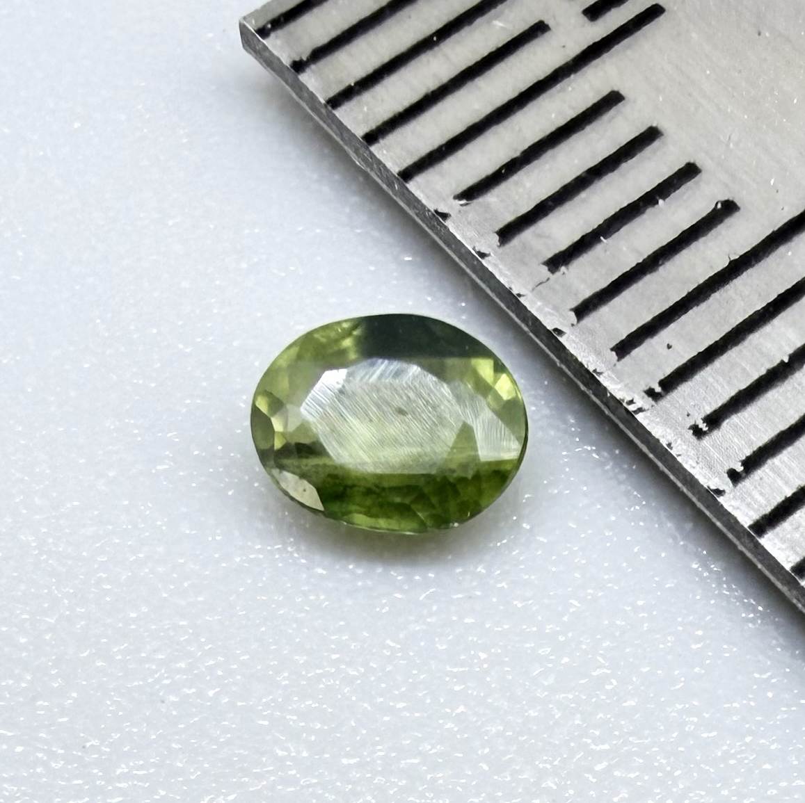 Oval green sapphire from Thailand, 0.37ct, unheated, with olive to deep green color zoning, visible natural inclusions and a transparent to slightly silky appearance.