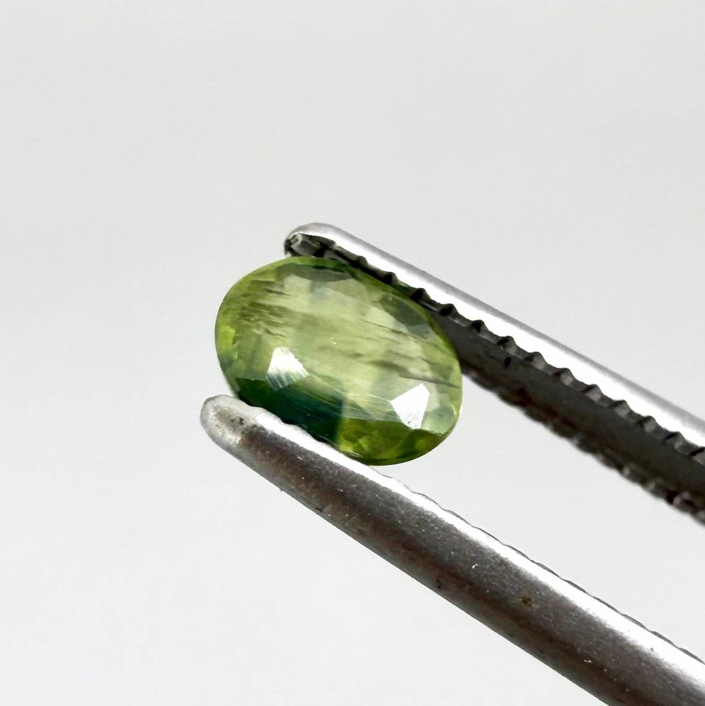 Oval green sapphire from Thailand, 0.37ct, unheated, with olive to deep green color zoning, visible natural inclusions and a transparent to slightly silky appearance.