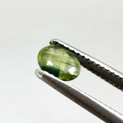 Oval green sapphire from Thailand, 0.37ct, unheated, with olive to deep green color zoning, visible natural inclusions and a transparent to slightly silky appearance.