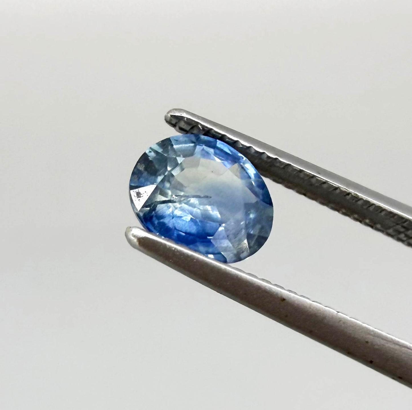 Oval cut light medium blue sapphire from Bangkaja, Thailand with natural color zoning and faceted brilliance.