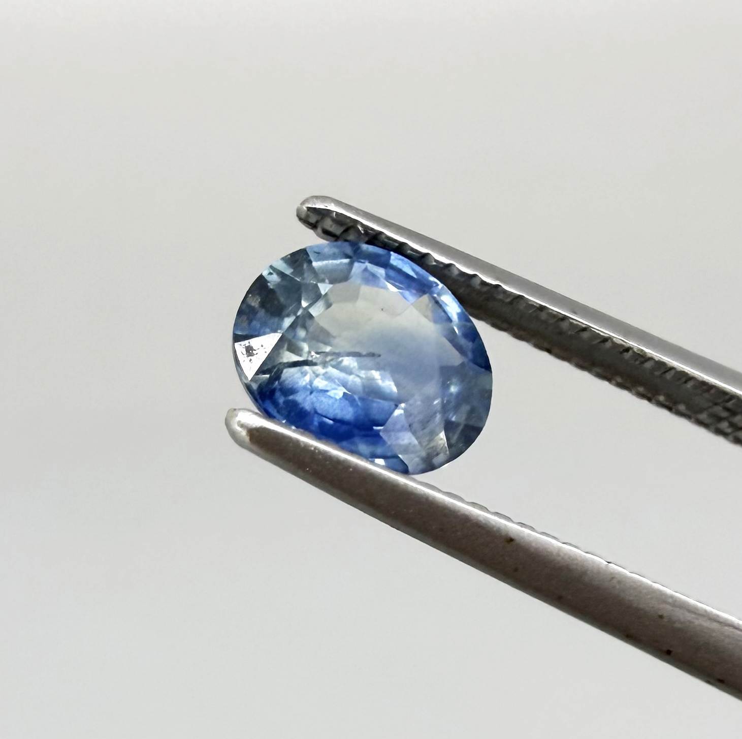 Oval cut light medium blue sapphire from Bangkaja, Thailand with natural color zoning and faceted brilliance.
