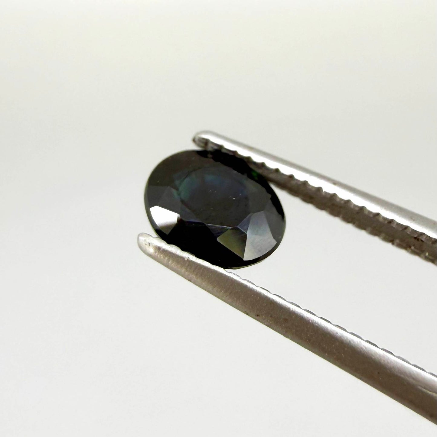 Oval dark blue heated sapphire from Laos weighing 0.87 ct, featuring a deep blue color and eye-clean clarity.